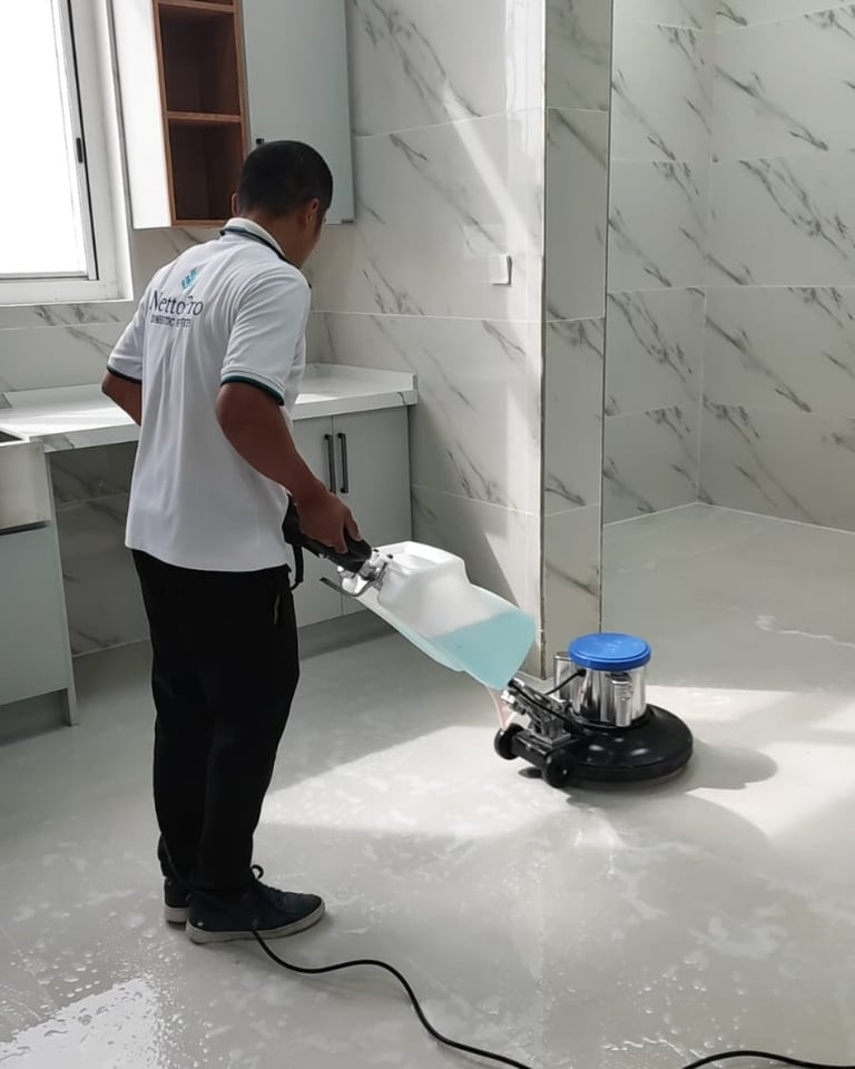 Worker cleaning white marble bathroom floor with electric polishing machine